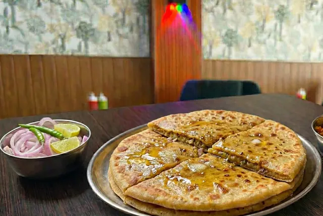 Sattu paratha, golden and stuffed, served with onion and lime