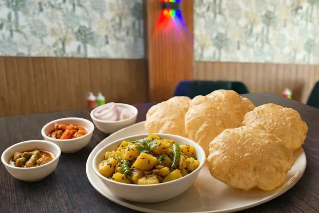 Fluffy puris served with a bowl of sabji