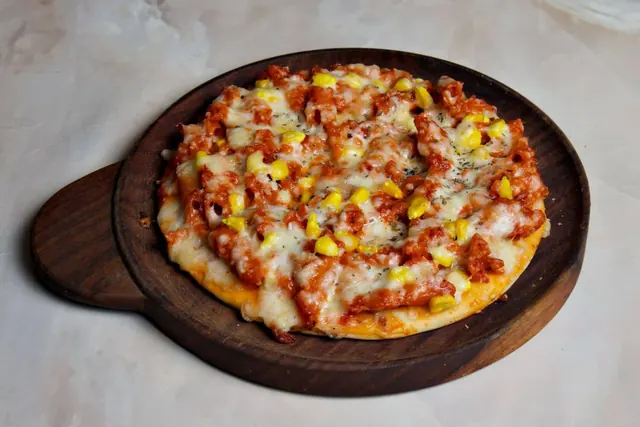 Pasta pizza with corn, peppers and melted cheese